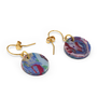 Two hook earrings featuring a round pendant in a marbled multicoloured pattern are laid out on a white background.