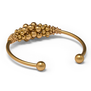 The back of a gold plated cuff bracelet adorned with gold beads.