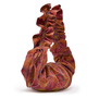 Red ruffle bag with blue and green stich details resting on a white surface.
