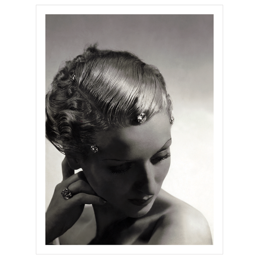 An atmospherically shadowed black and white portrait photograph of a demure model with diamond hairclips