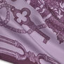 Close up of a pink and purple scarf with a print featuring an ornate key and details of jewellery.