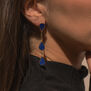 A close up of the neck and ear of a woman wearing a drop earring featuring three teardrop shaped lapis lazuli stones each.