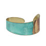 A brass cuff bracelet painted with a turquoise and brown patina. The inside of the bracelet shows the golden colour of the brass base.