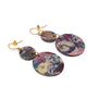 A pair of hook earrings laid down on a white surface. They both feature two flat round pendants in different sizes, each featuring a marbled multicoloured pattern.