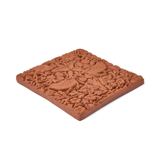 A terracotta tile featuring a floral design with two birds.