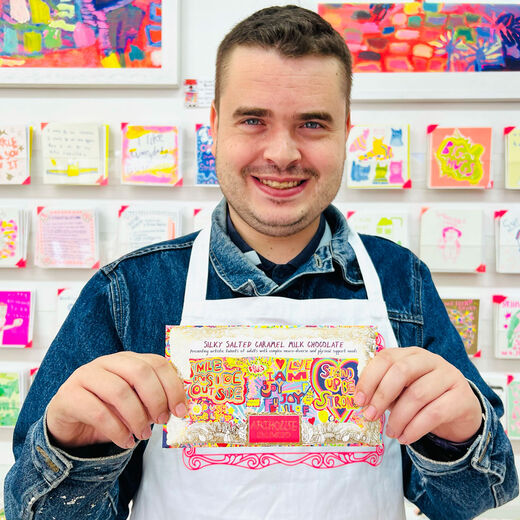 ARTHOUSE Unlimited artist holds a packet of chocolate bar to the camera.