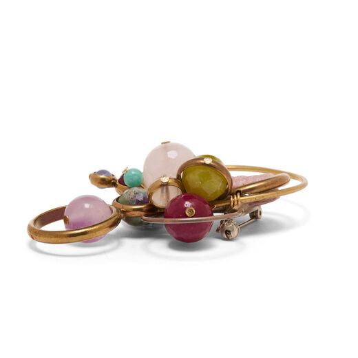 Side view of a brooch featuring pastel pink and green beads set on brass hoops.