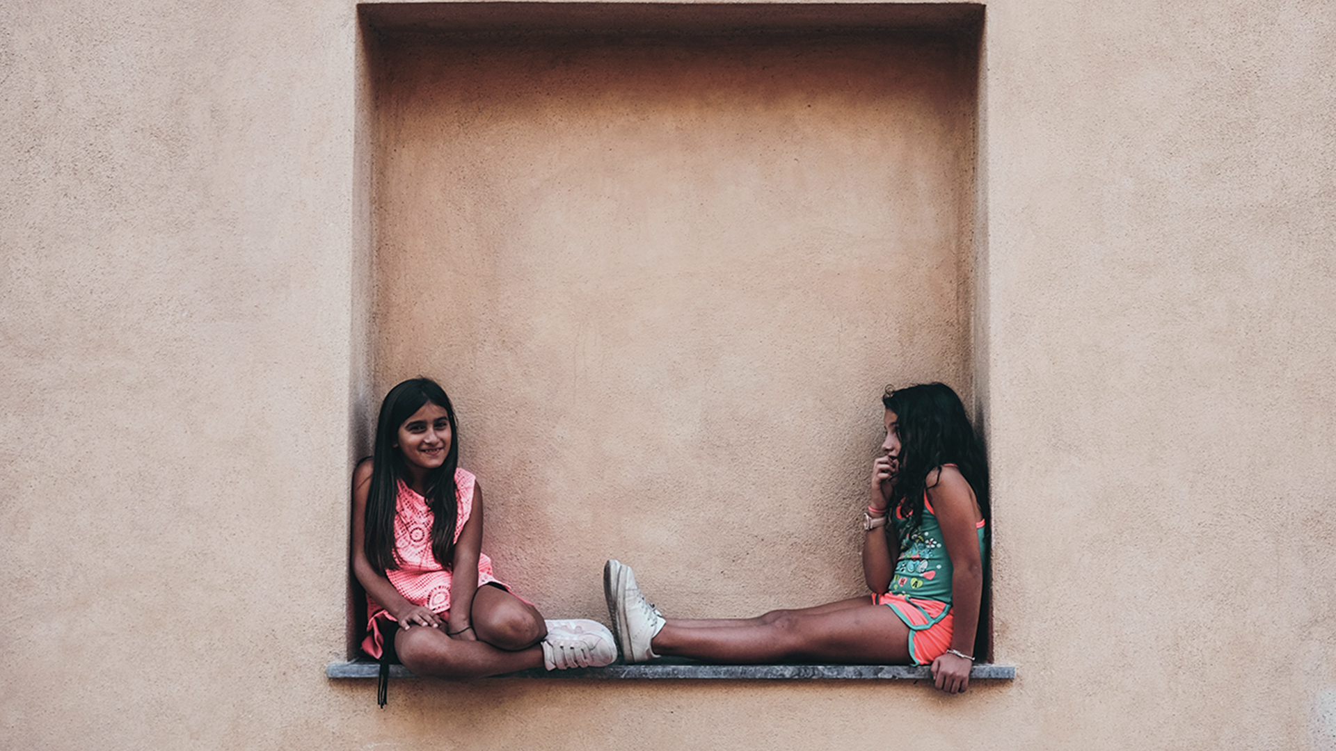 Two girls sitting on a wall shelf