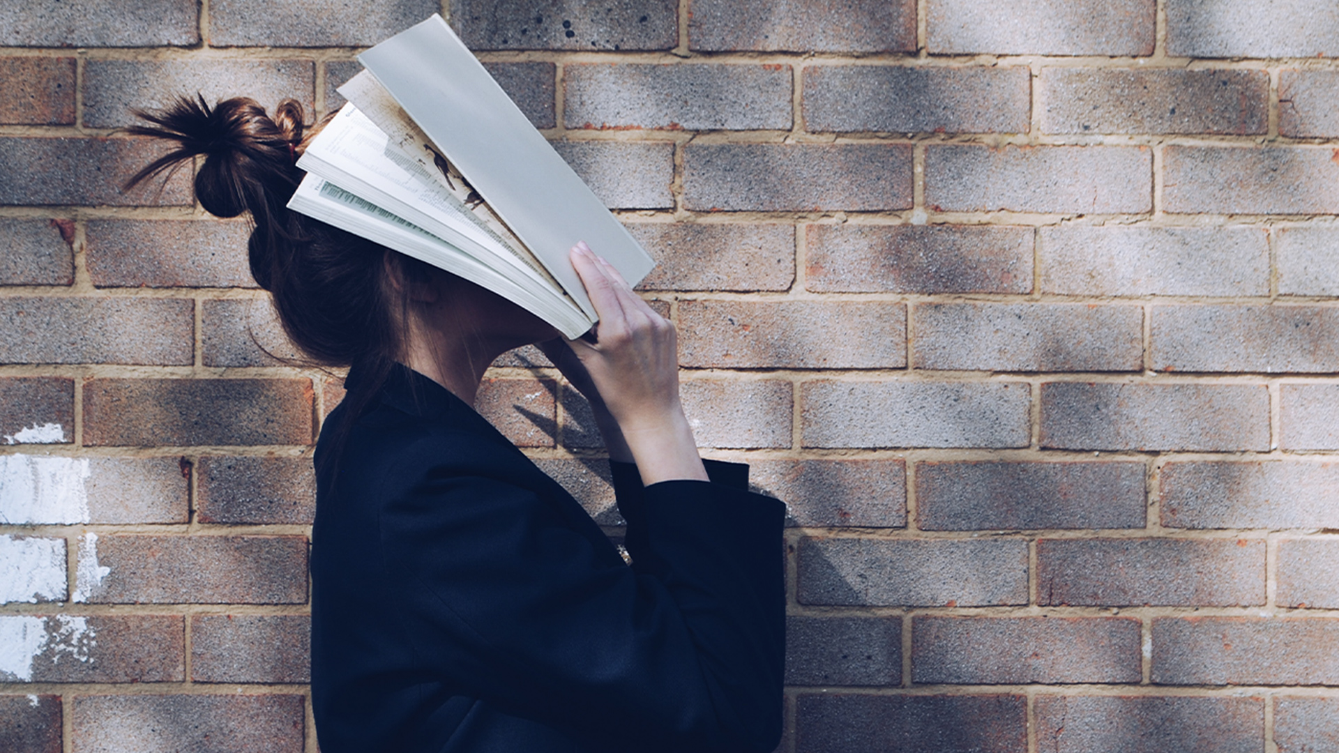 A woman covering her face with her book