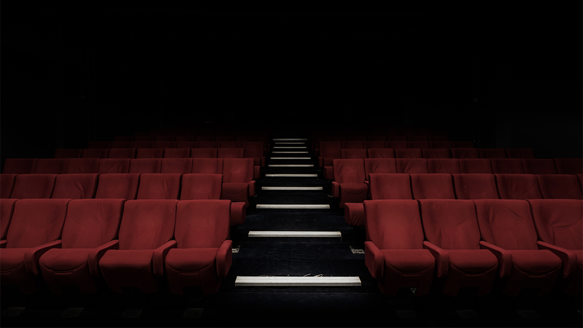 Red cinema chairs in darkness