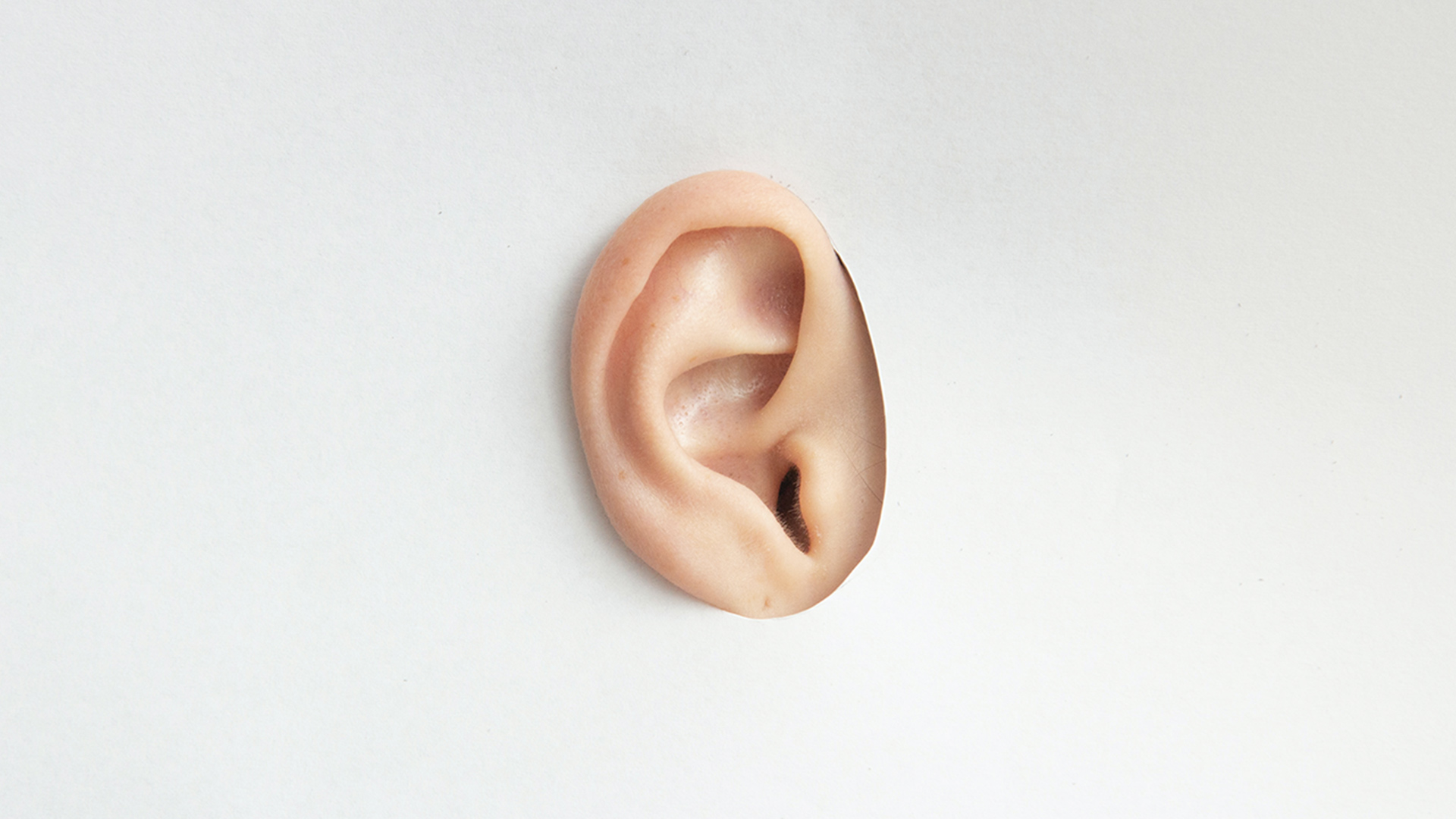 Ear listening through a cardboard hole