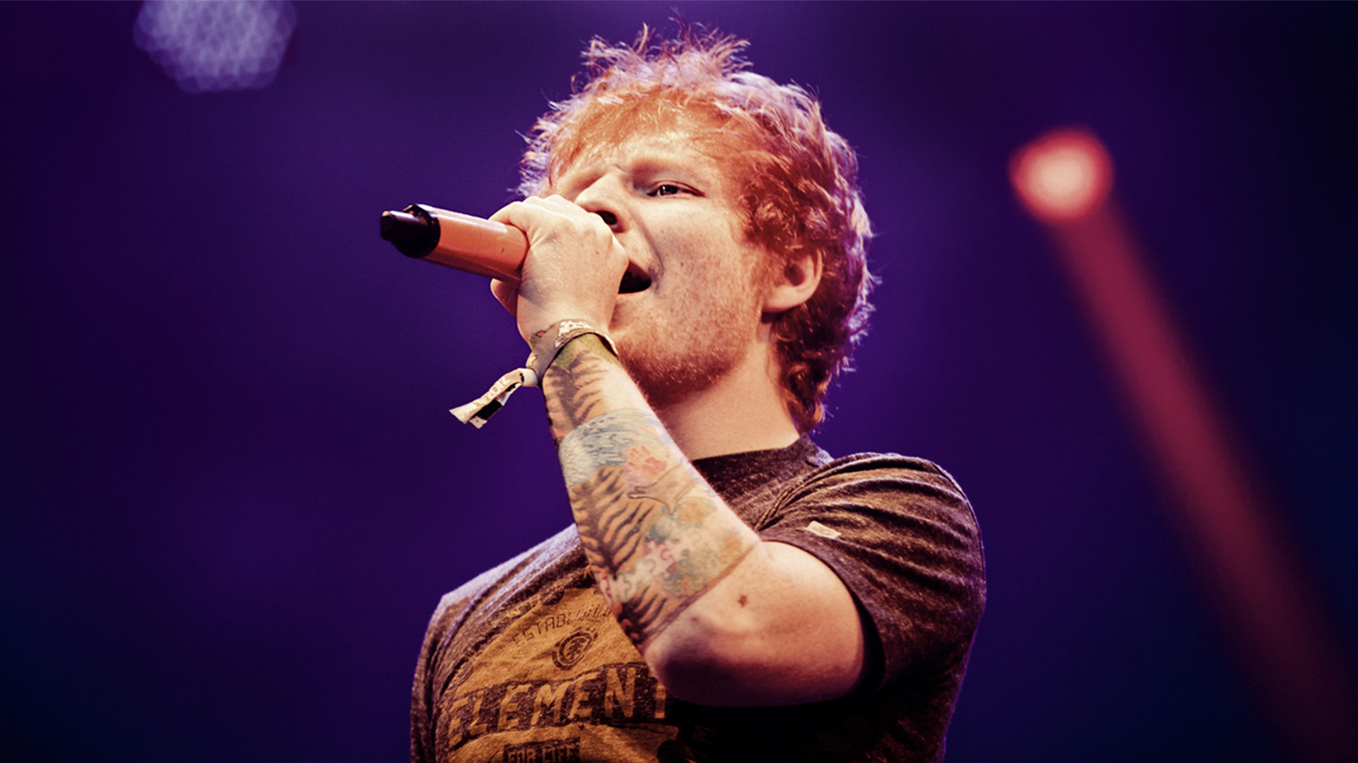 Ed Sheeran singing into a microphone