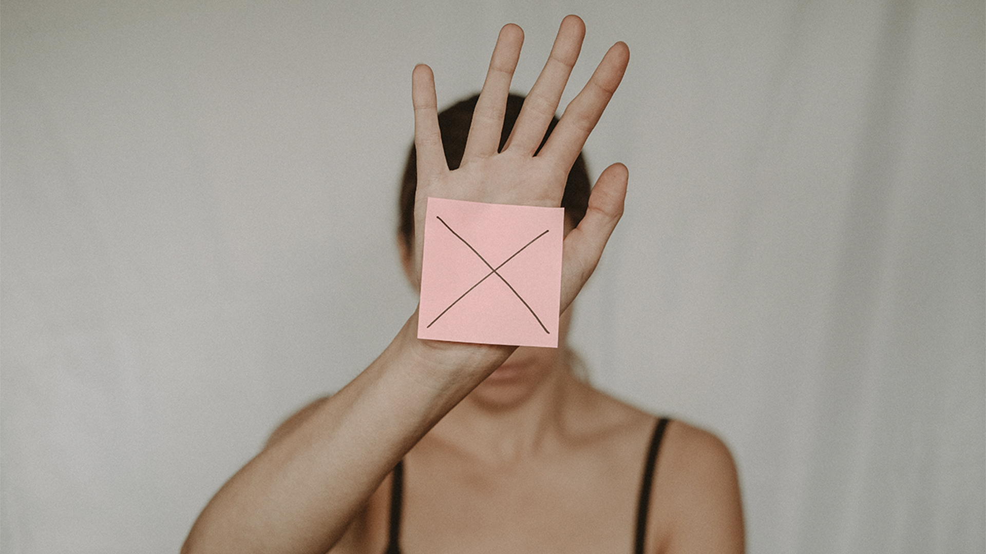 Woman holding post-it with cross on it