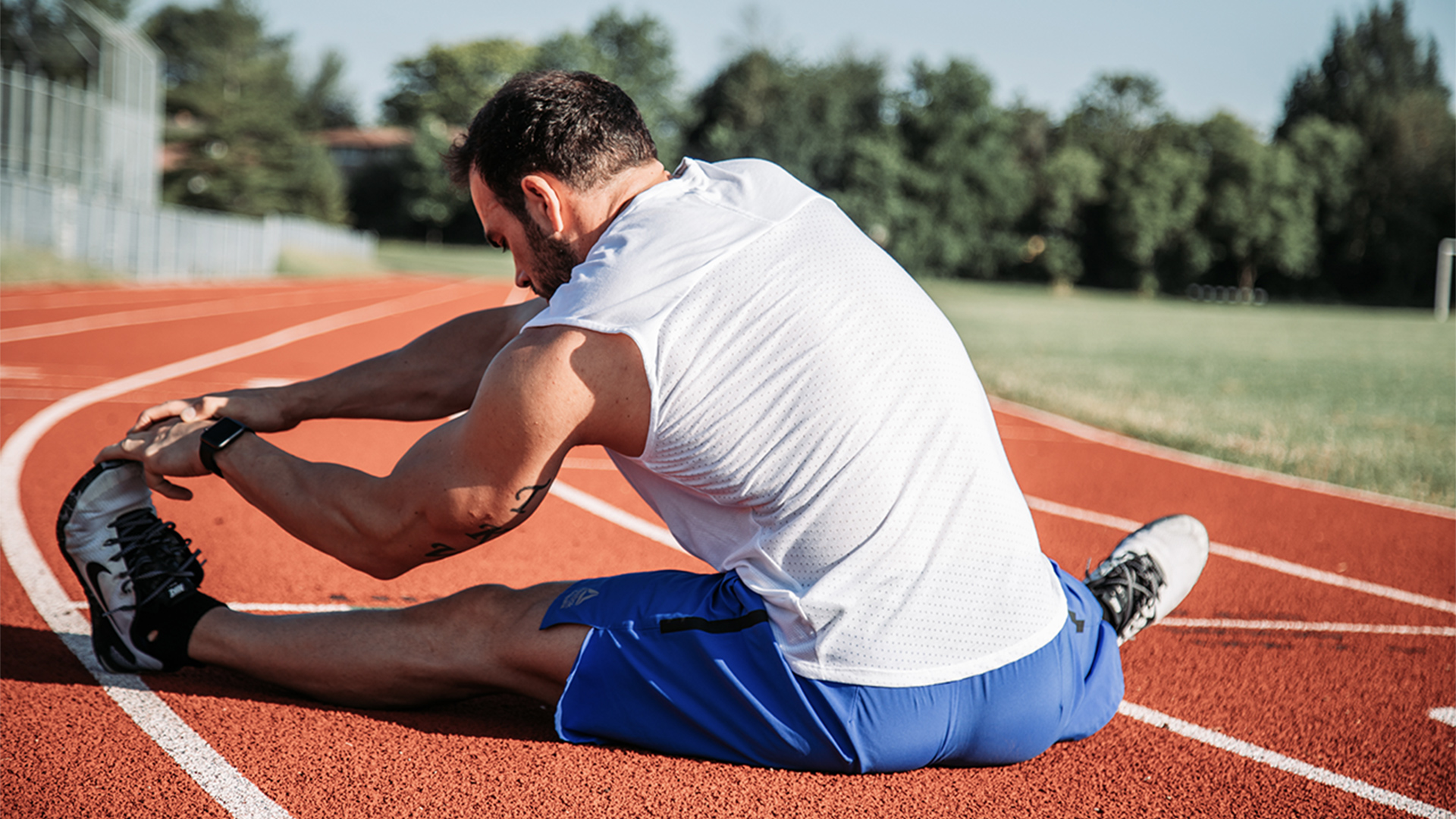 An athlete stretches on a running track