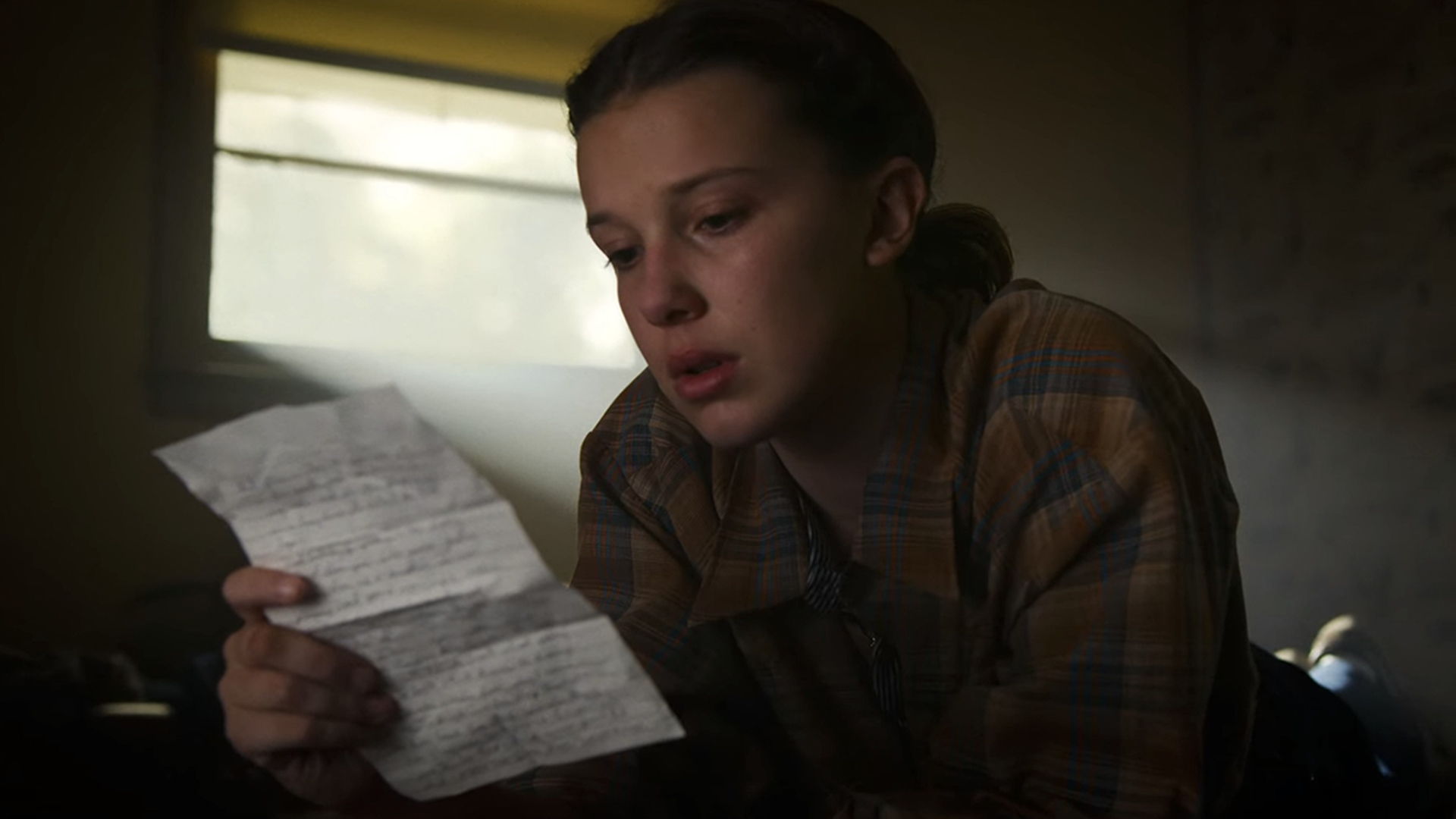 Eleven from Stranger Things reading a letter