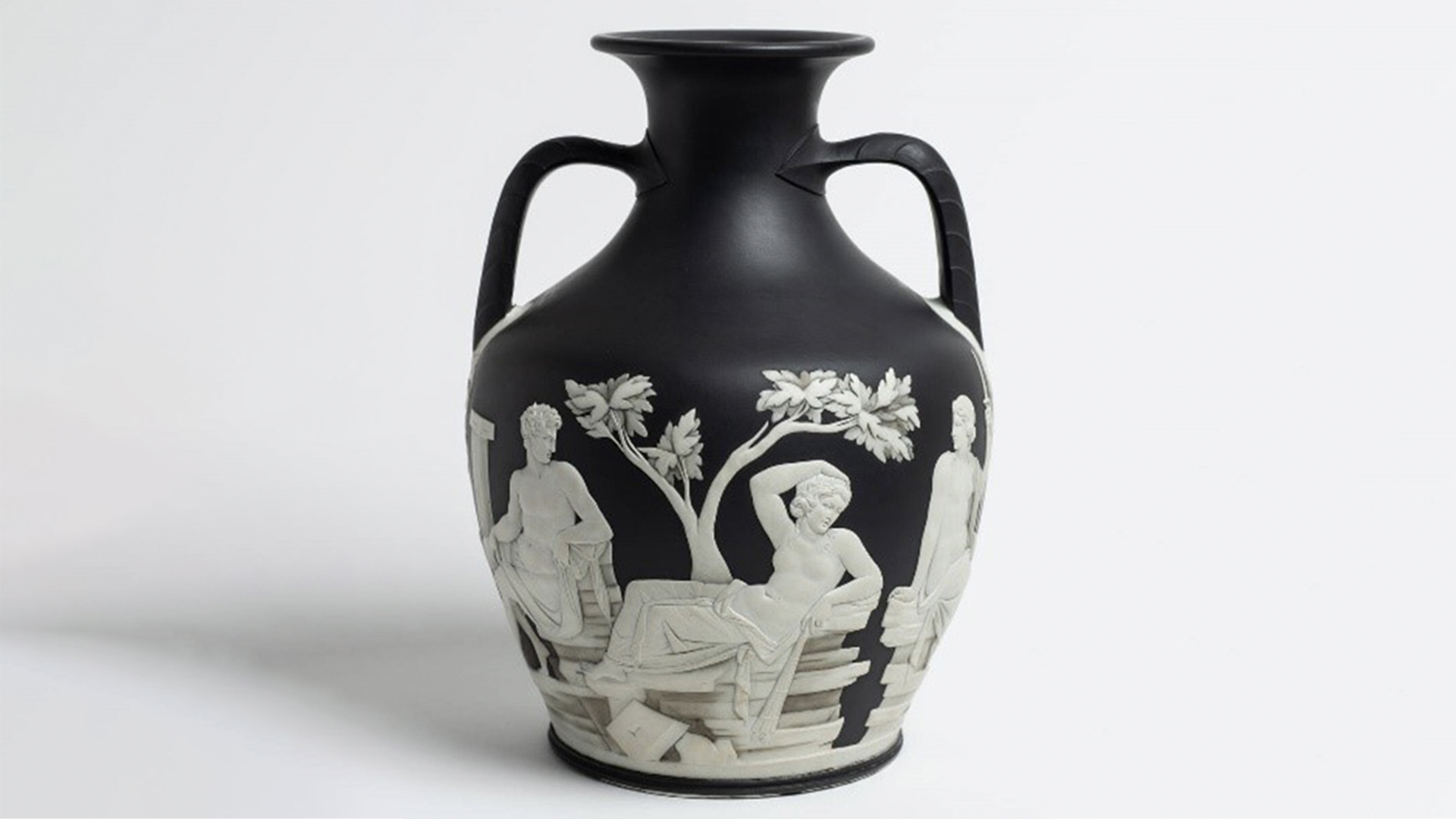 Black ceramic vase with decorative figures and leaves