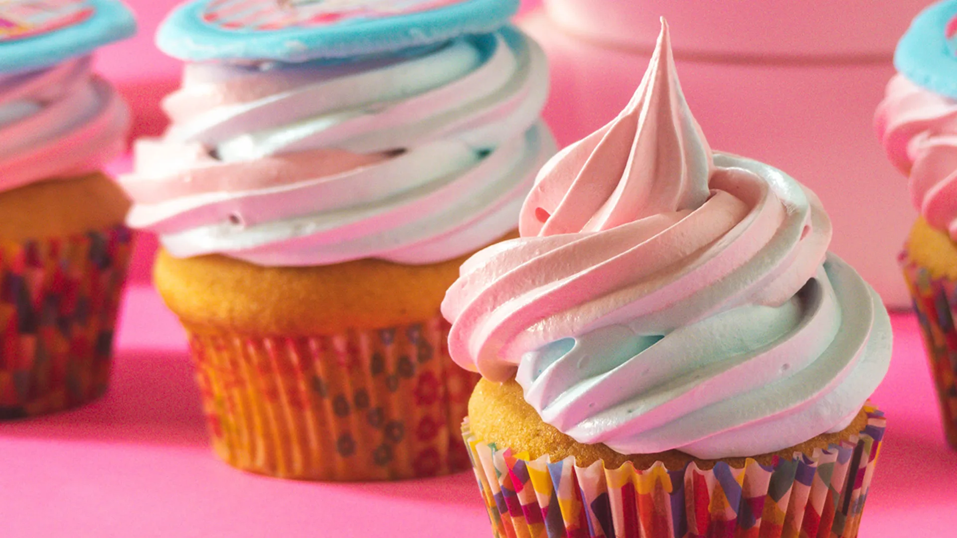 Colourful fluffy cupcakes one a pink background