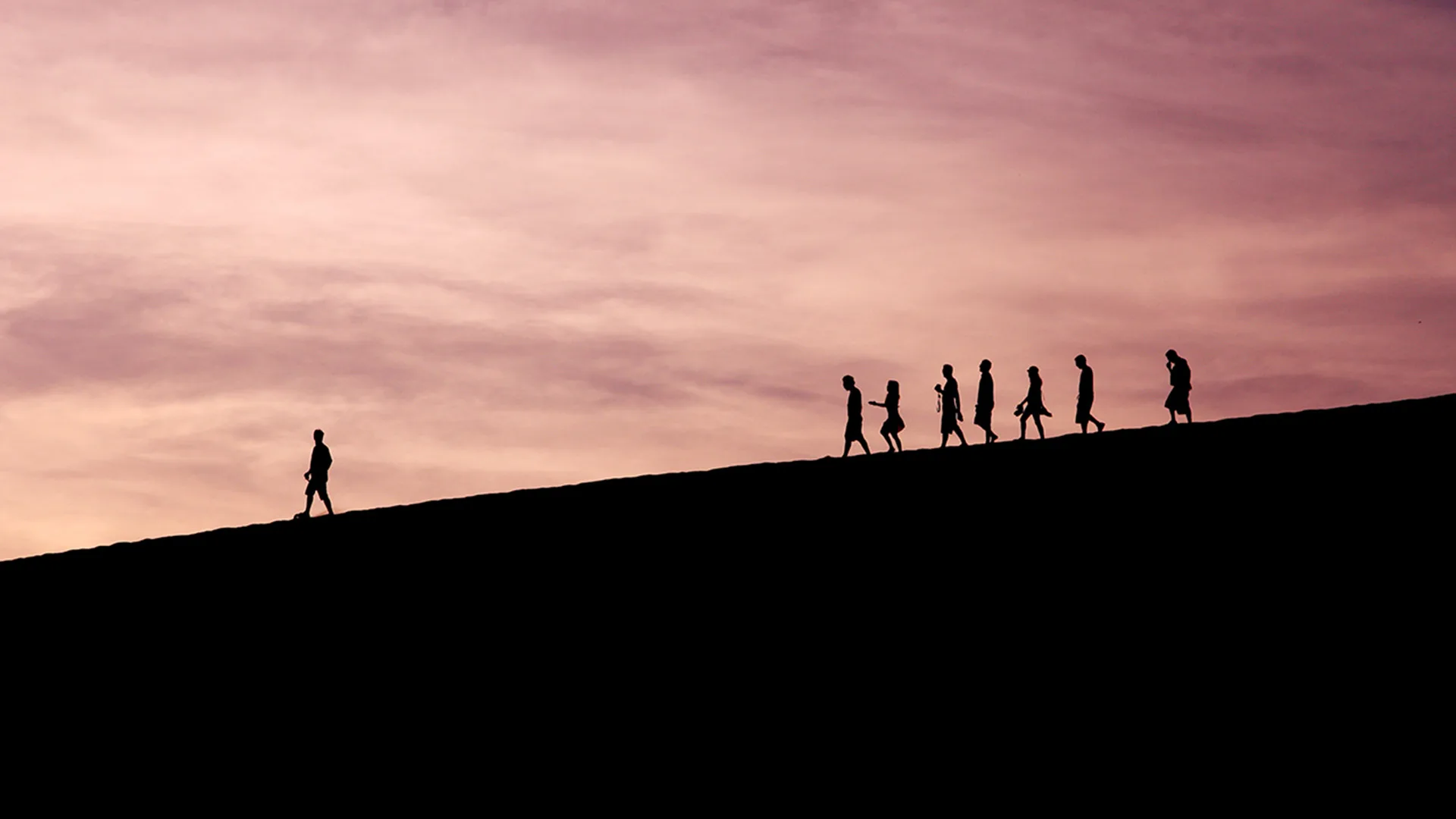 A silhouette of people walking down a hill