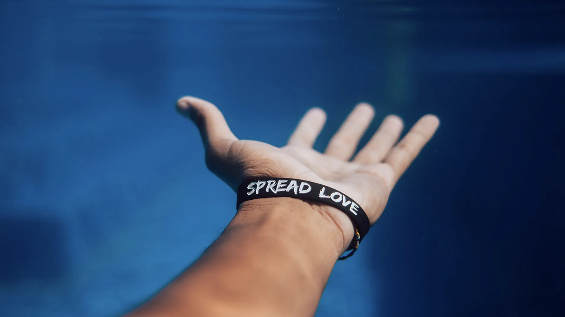 A hand with a bracelet that says Spread Love