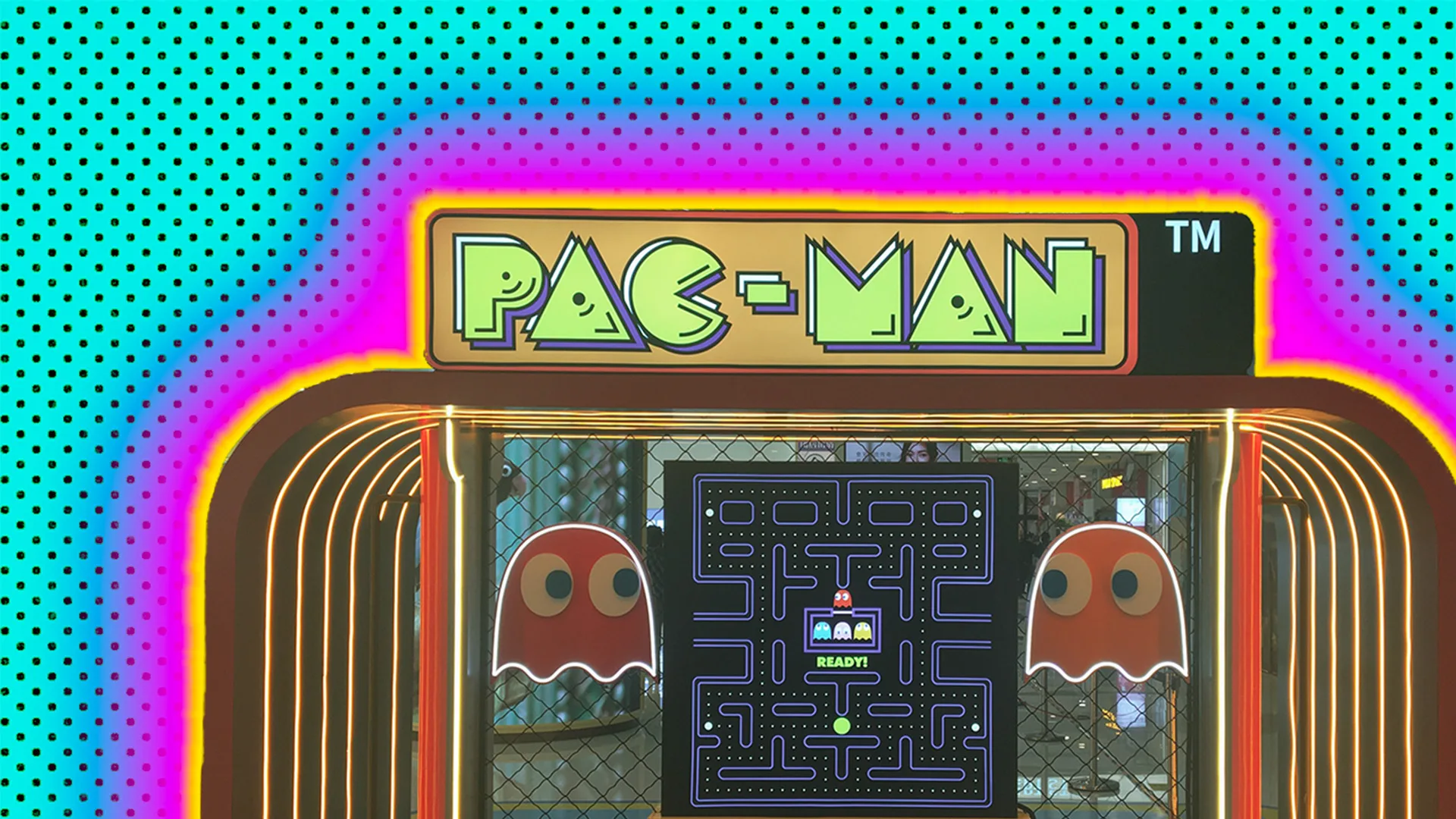 A retro Pacman games console outlined by a pink glow effect on a turquoise dotted background