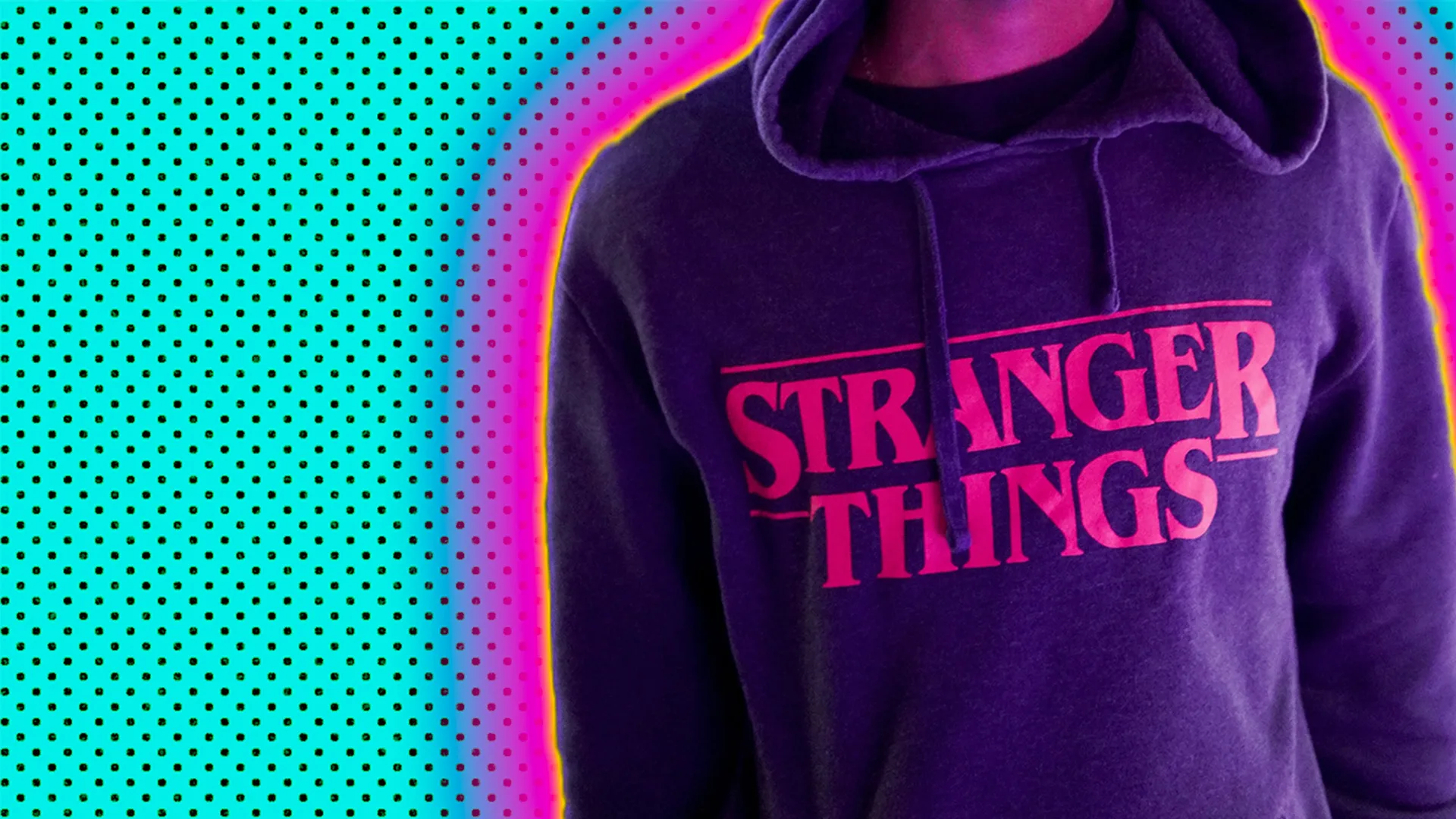 A close up of a hoodie with the Stranger Things logo outlined by a pink and yellow glow against a turquoise background
