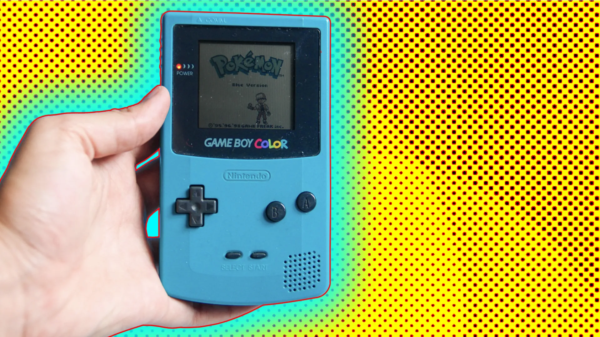 Someone holding a Pokemon Blue game on the gameboy colour. The background is yellow and there is a blue glow around the hand and the game device