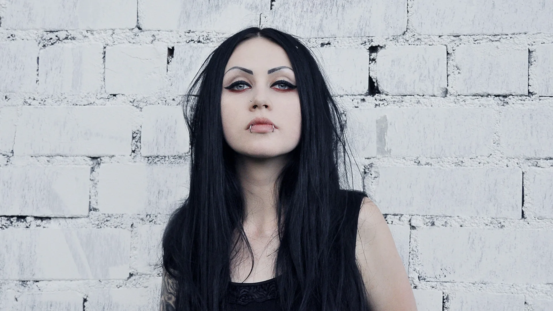 A woman standing in front of a white wall with heavy makeup