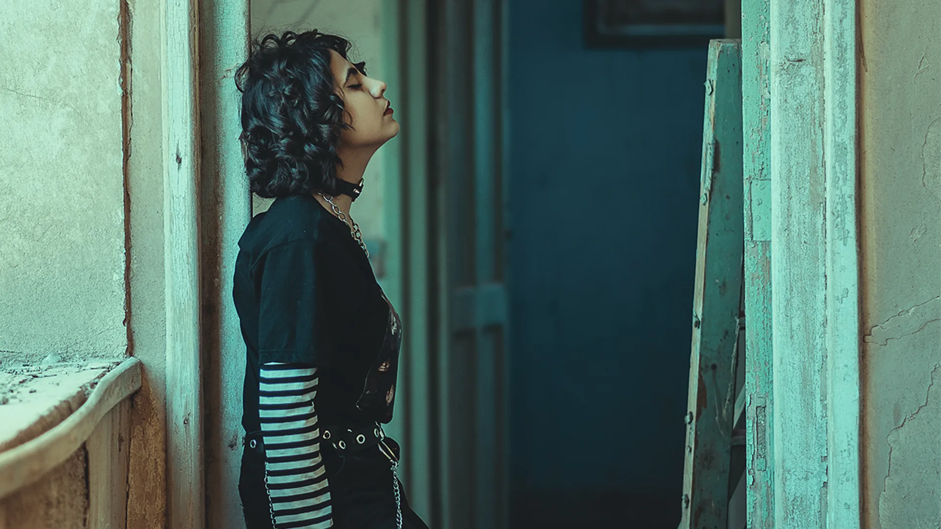 A woman leaning on a doorframe wearing black