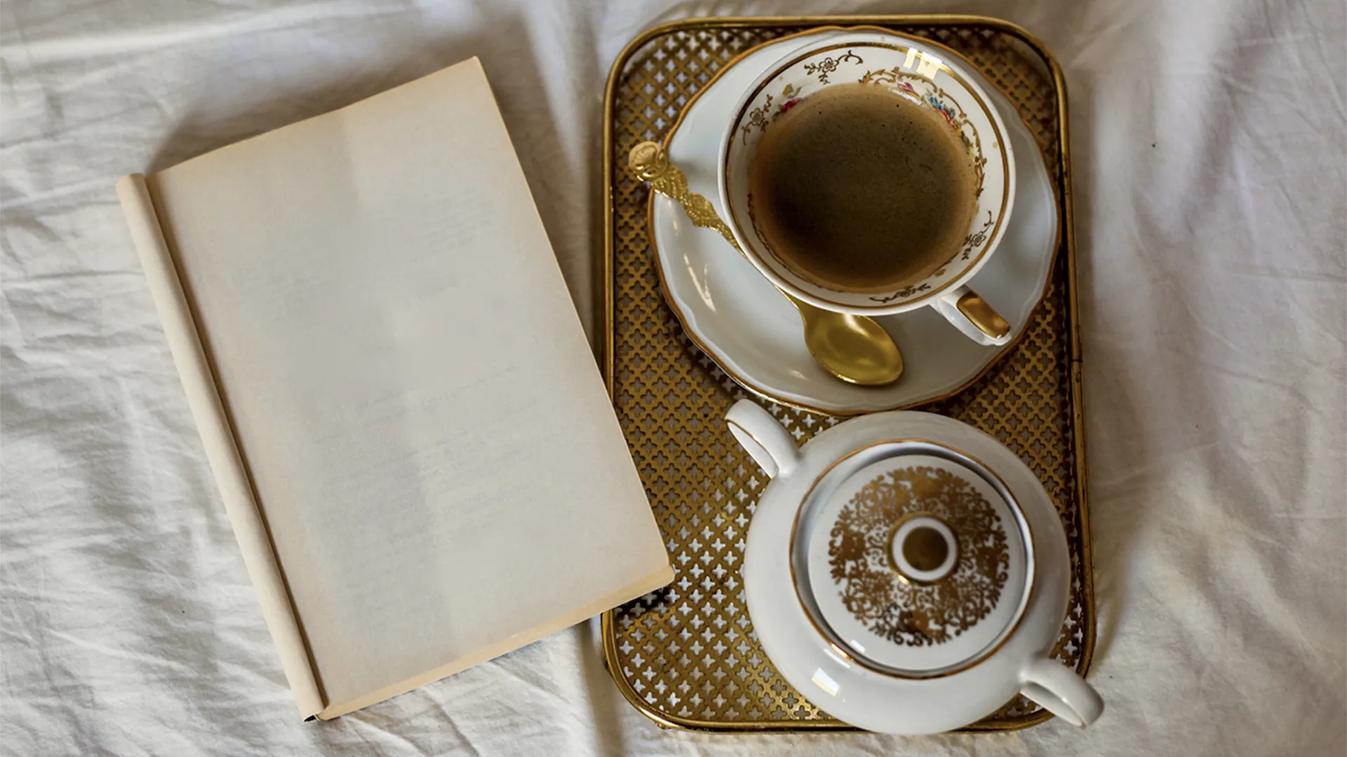 A empty book next to a tea cup and teapot