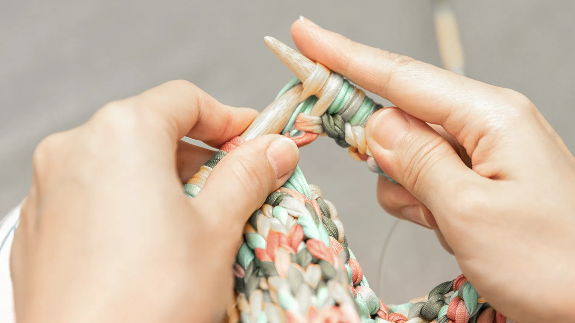 Someone knitting with a colourful, pastel yarn