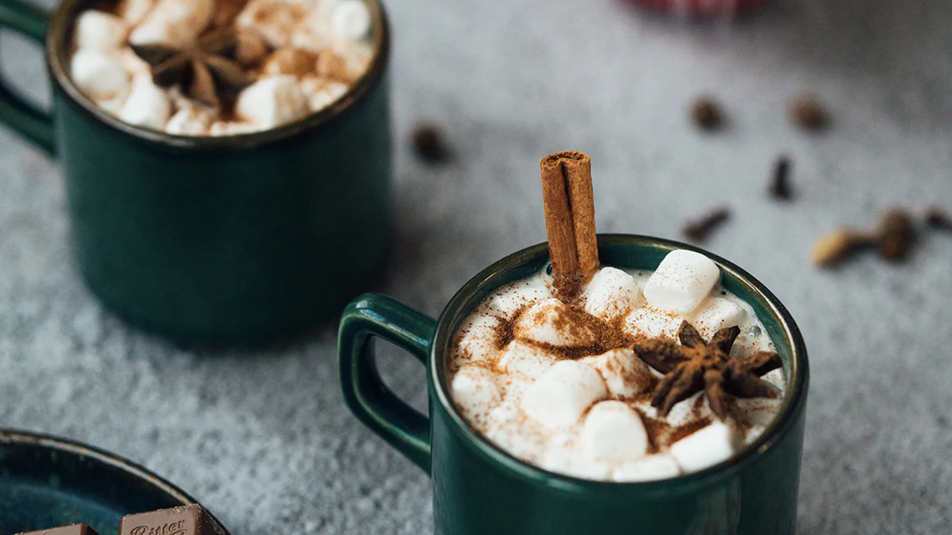 Hot chocolates with whipped cream and cinnamon placed on a table