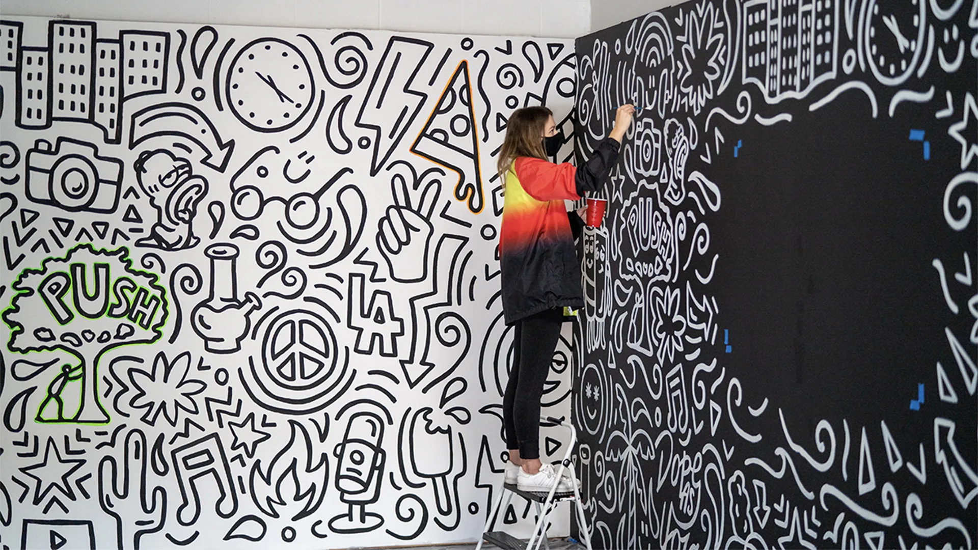 A woman painting a mural on a wall
