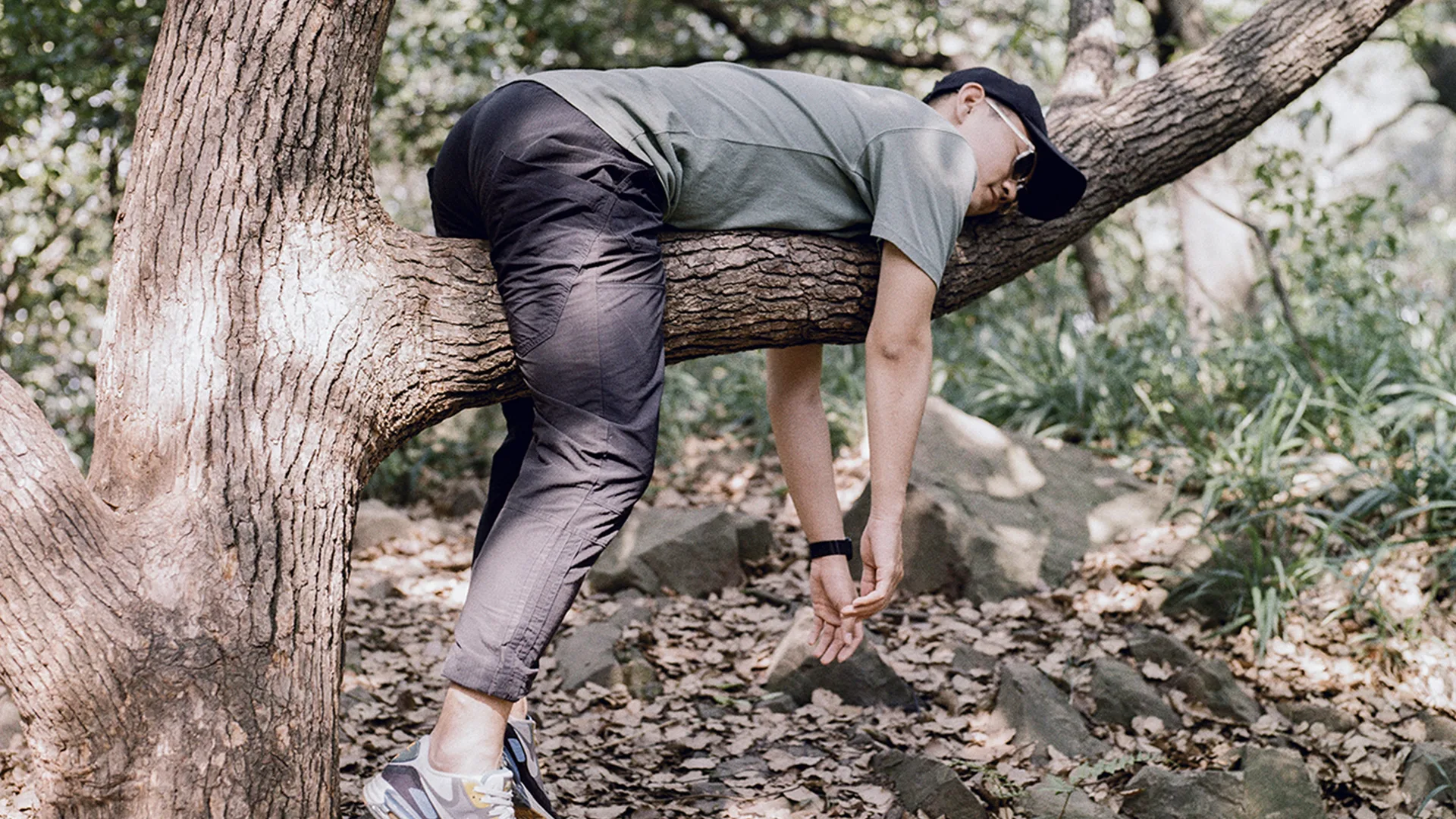 Man relaxing over a tree branch in a woods