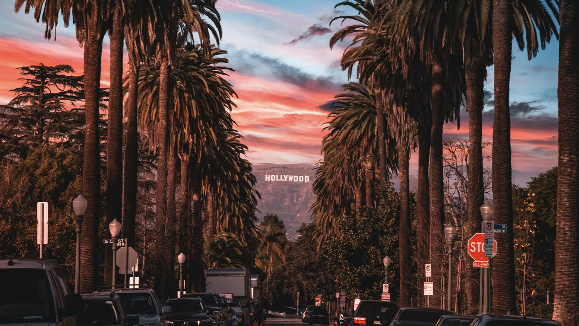 Hollywood sign in between palm trees at sunset