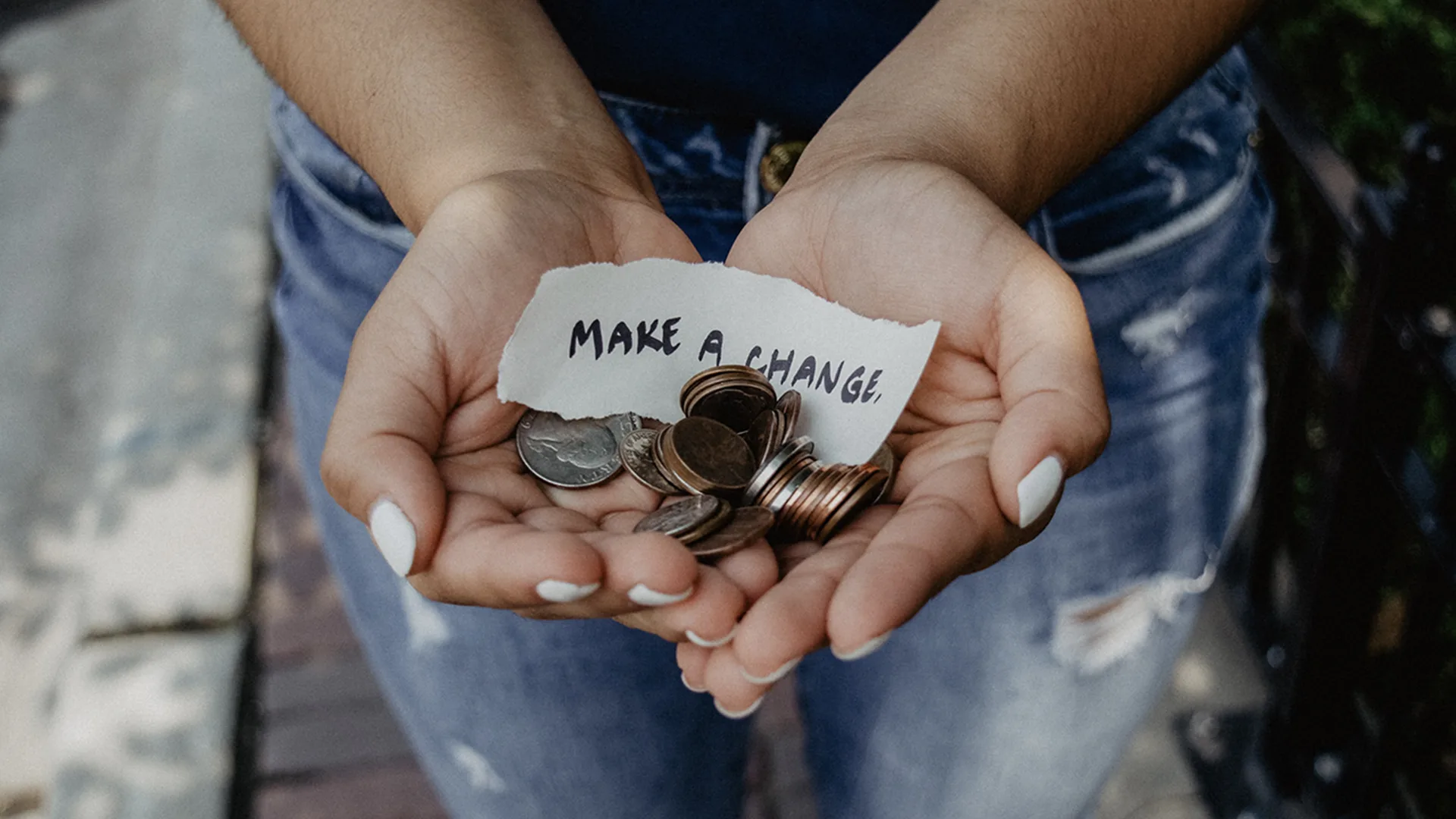 A woman holding some money with the note 'make a change'