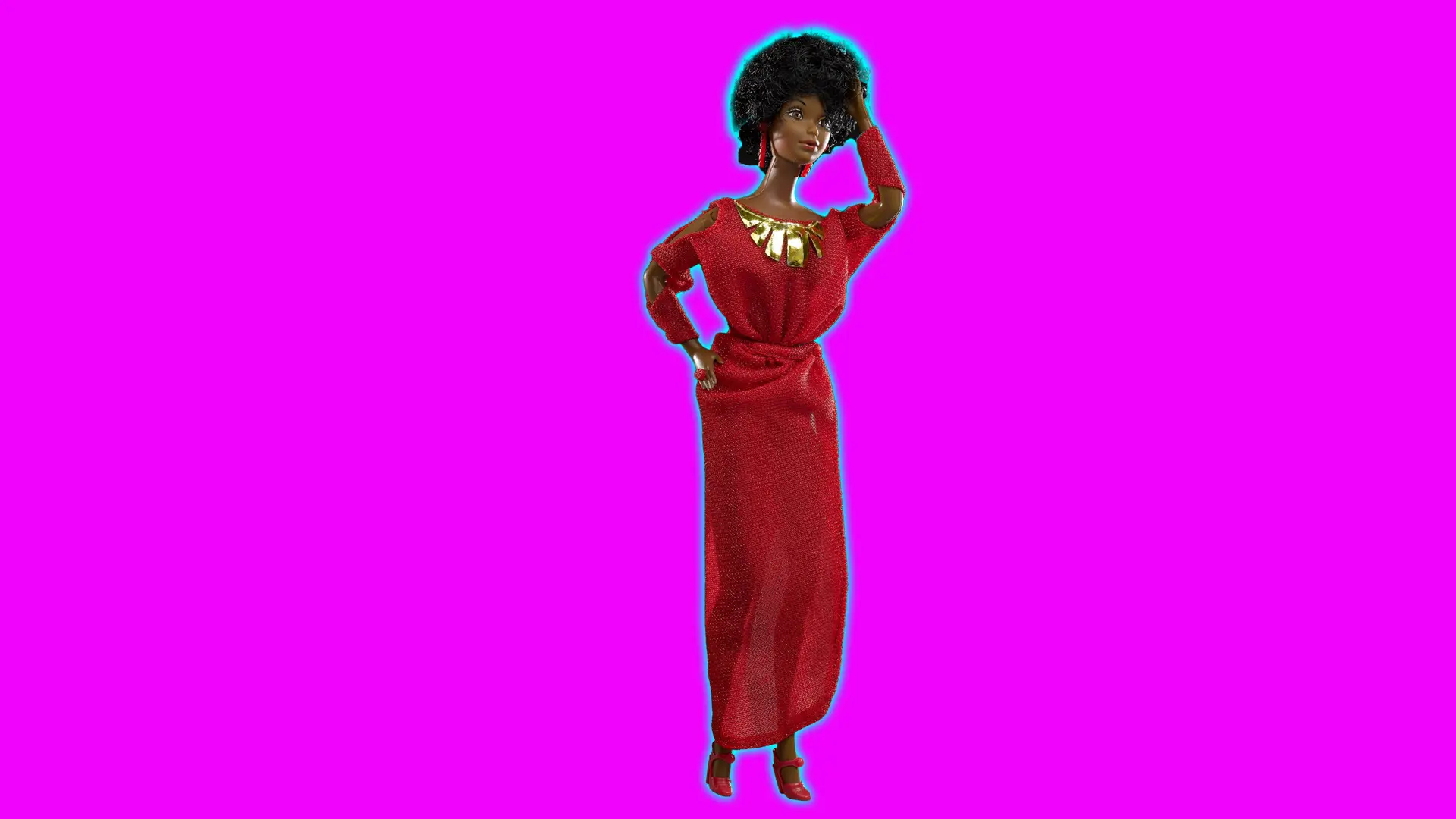 A photo of a barbie called Kitty Black Perkins, a dark skinned Barbie in a red dress with gold necklace stood against a pink background with blue halo.