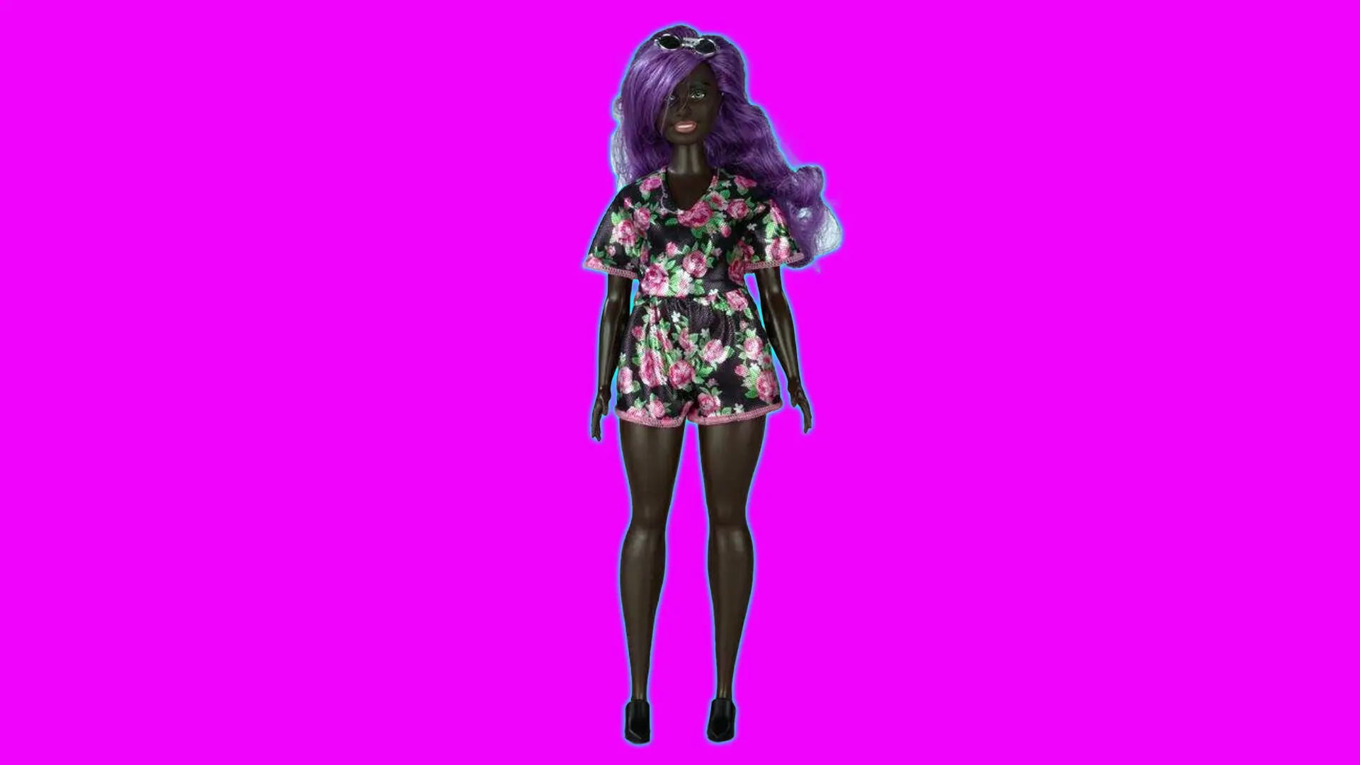 A photo of a dark skinned Barbie doll wearing a playsuit with purple hair set against a pink background with a blue halo.