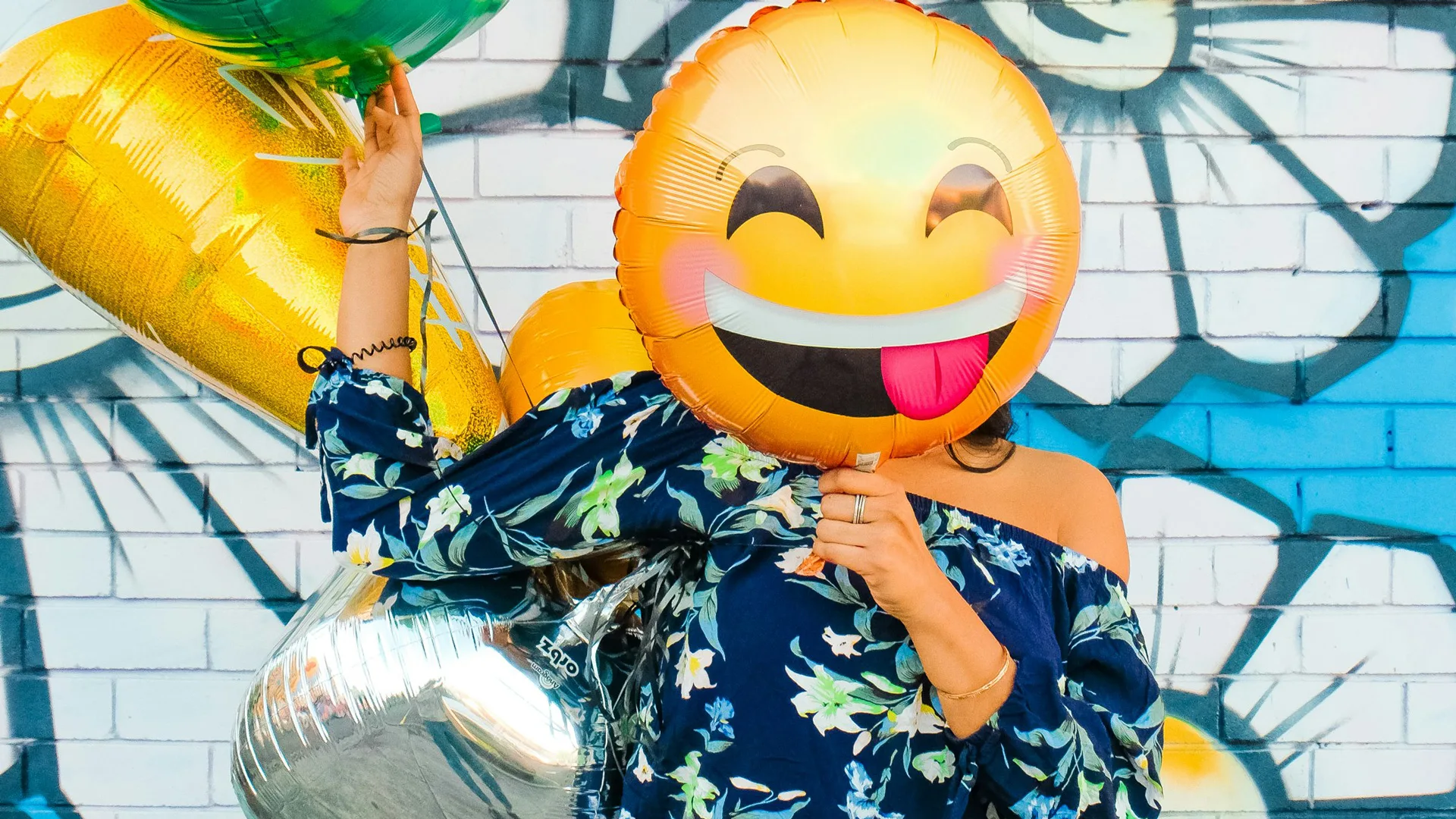 A photograph of a woman holding a balloon of a smiling emoji