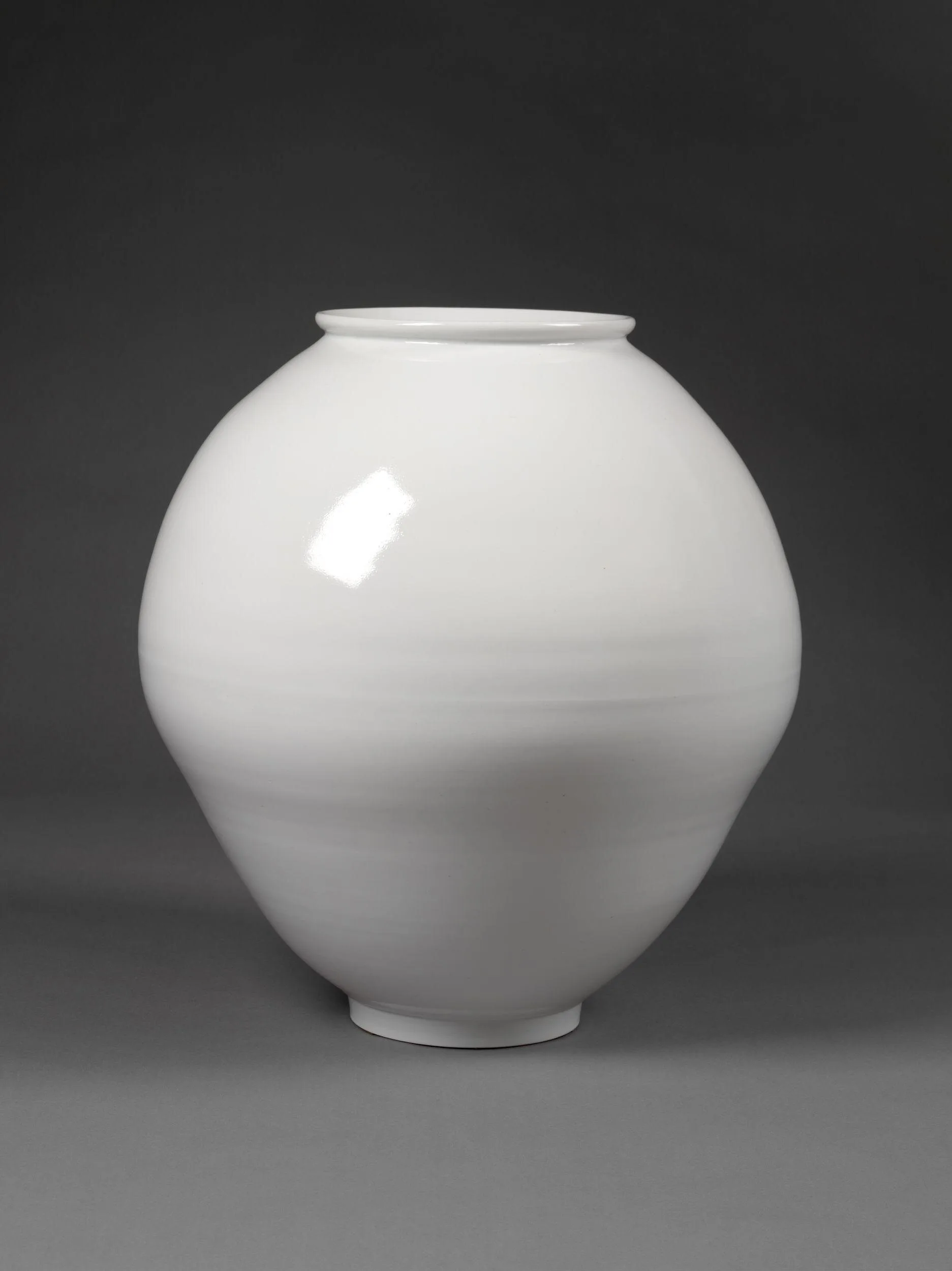A photo of the white moon jar on a grey background made by Young Sook Park