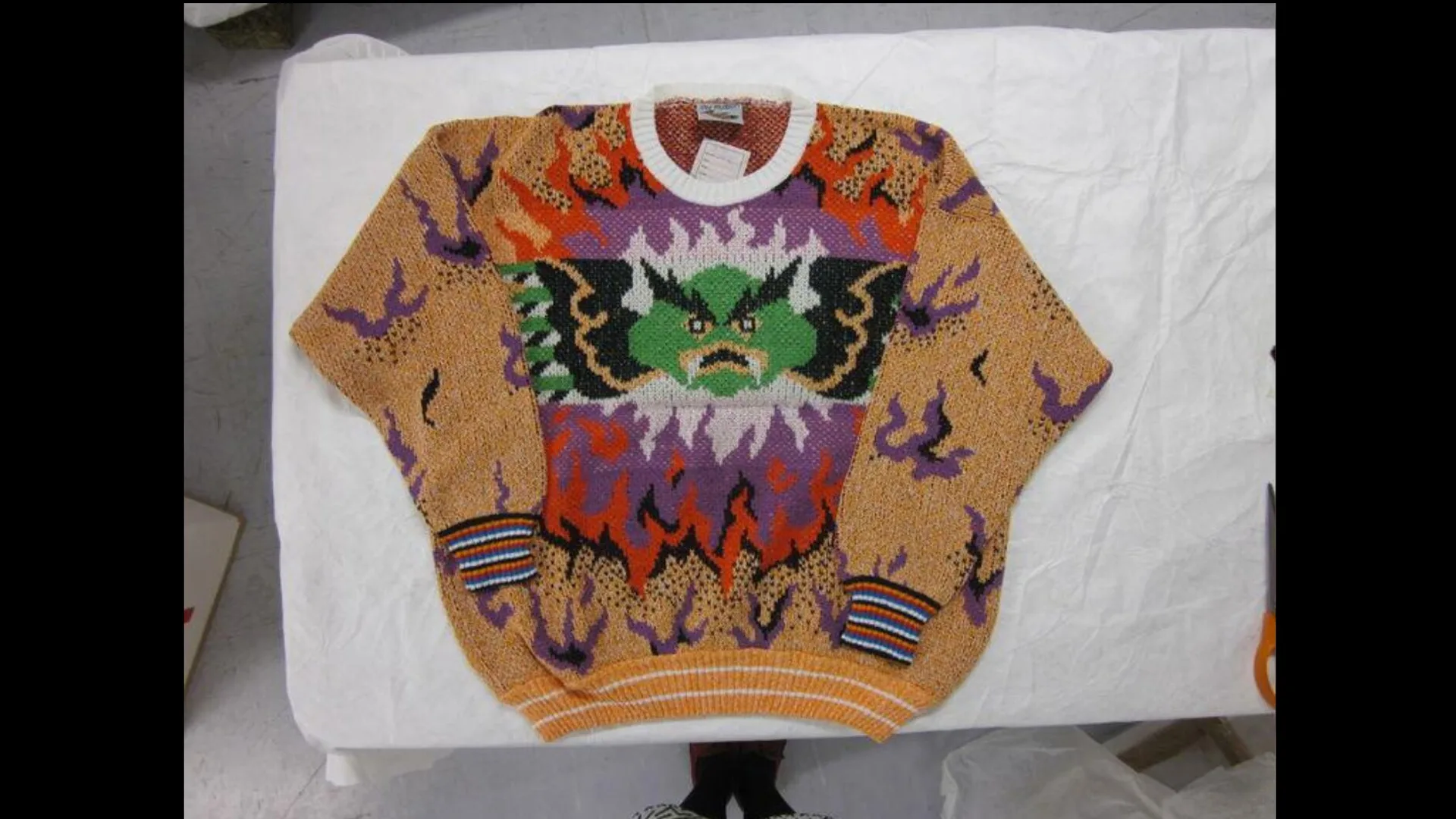 Photograph of a knitted jumper with an angry dragon design