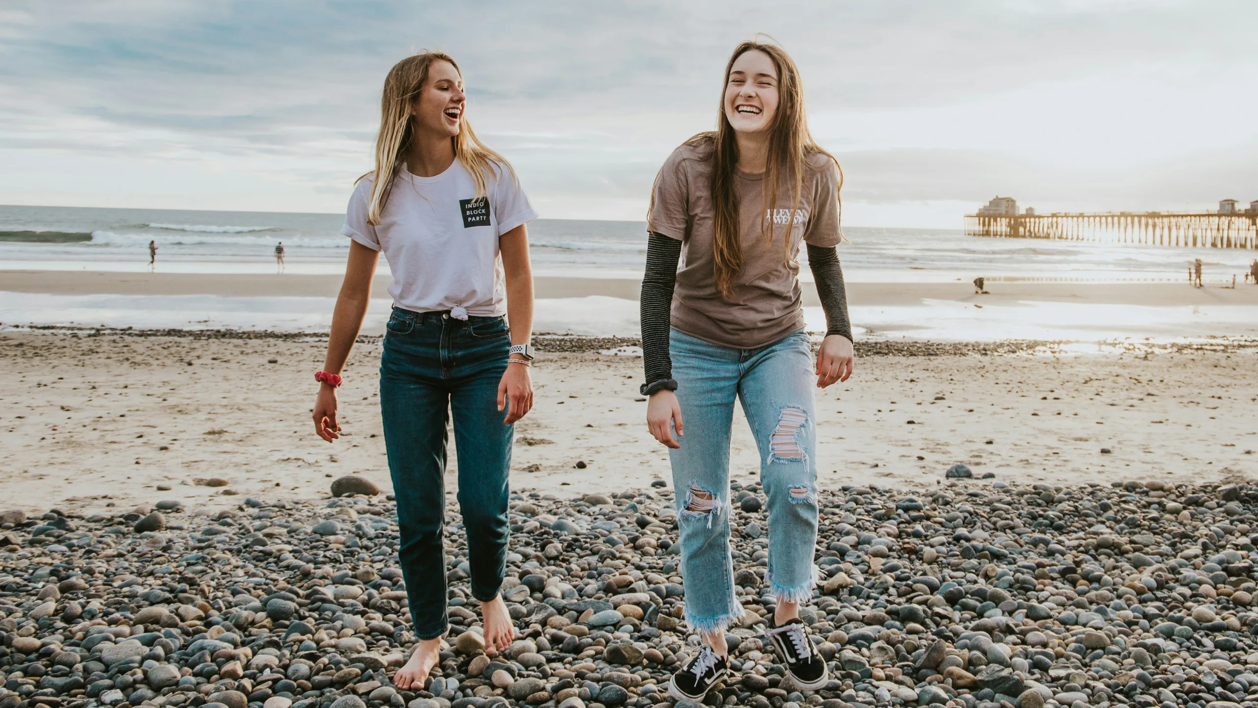 A photograph of two women walking on the beach