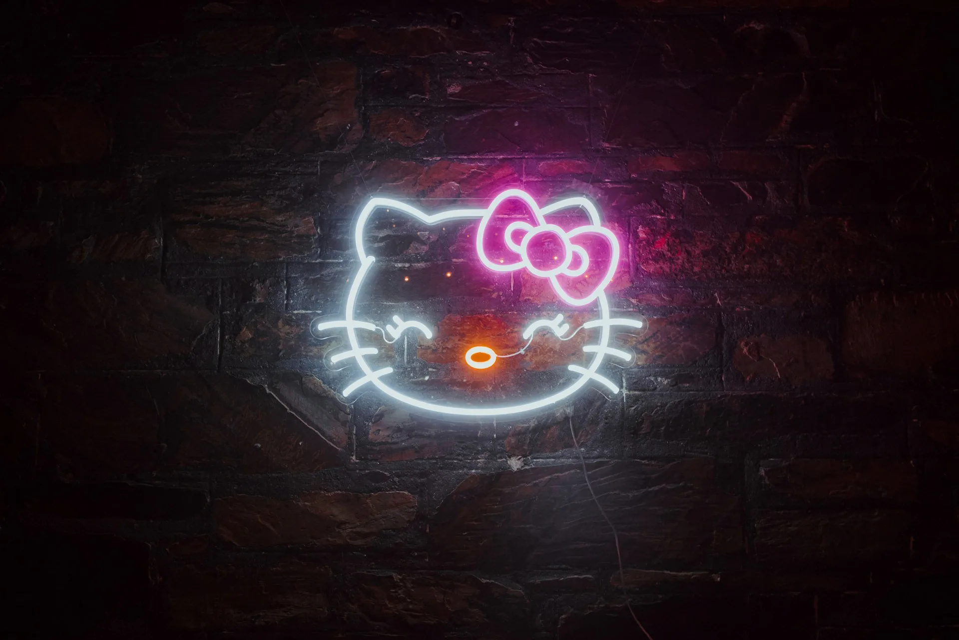 Hello Kitty logo neon sign on brick wall
