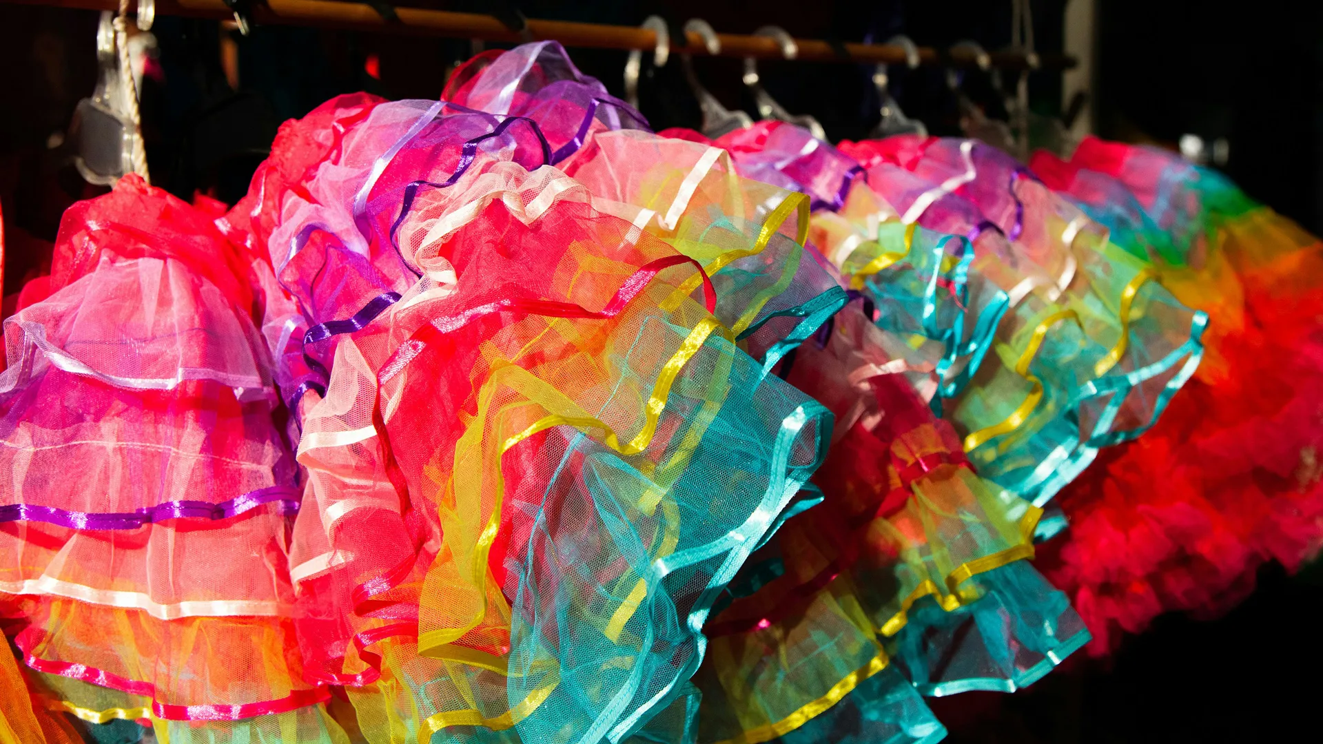 A photograph of colourful tutus hanging on a rack
