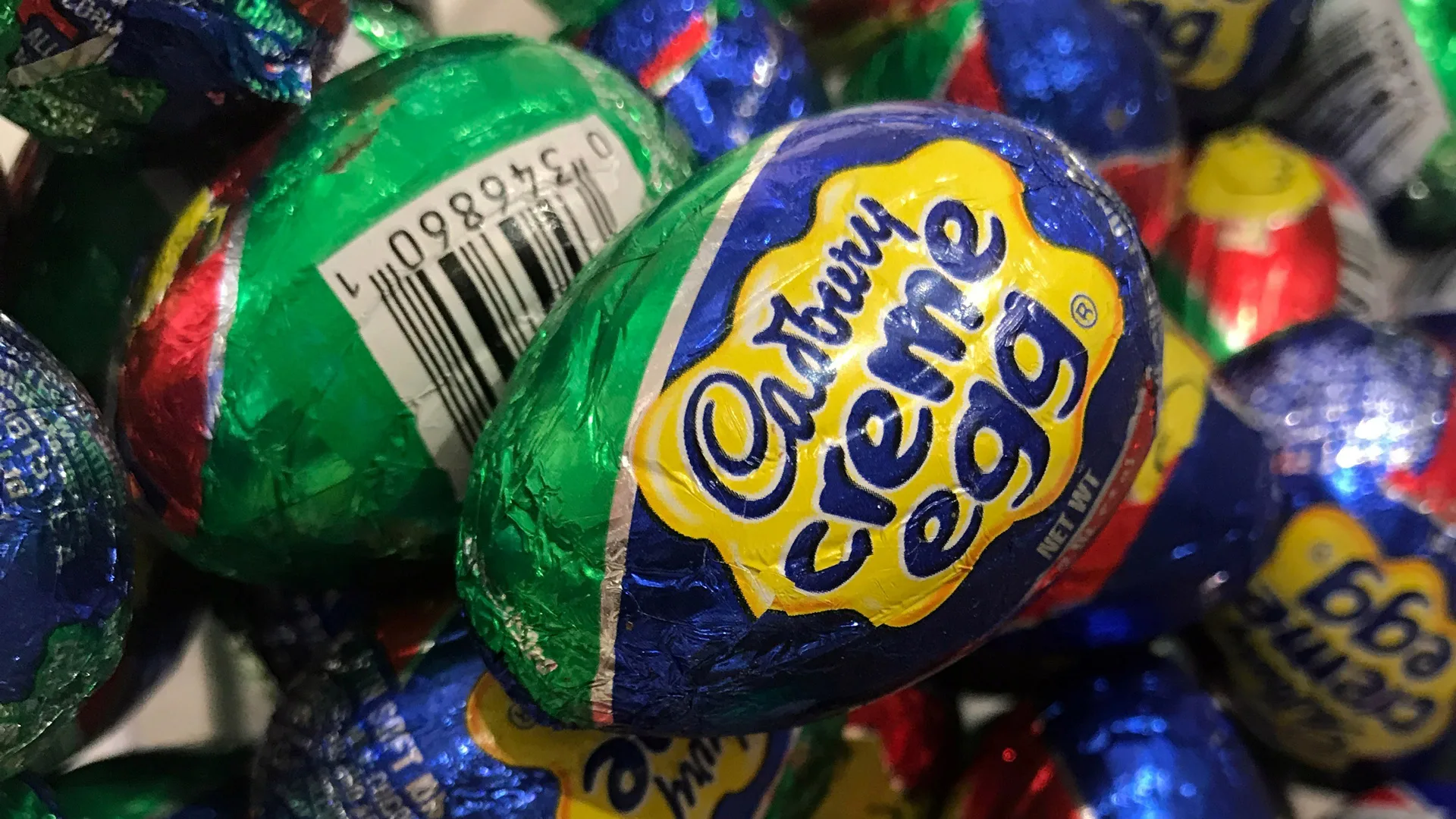 A close-up photograph of a Cadbury creme egg in it's foil wrapping
