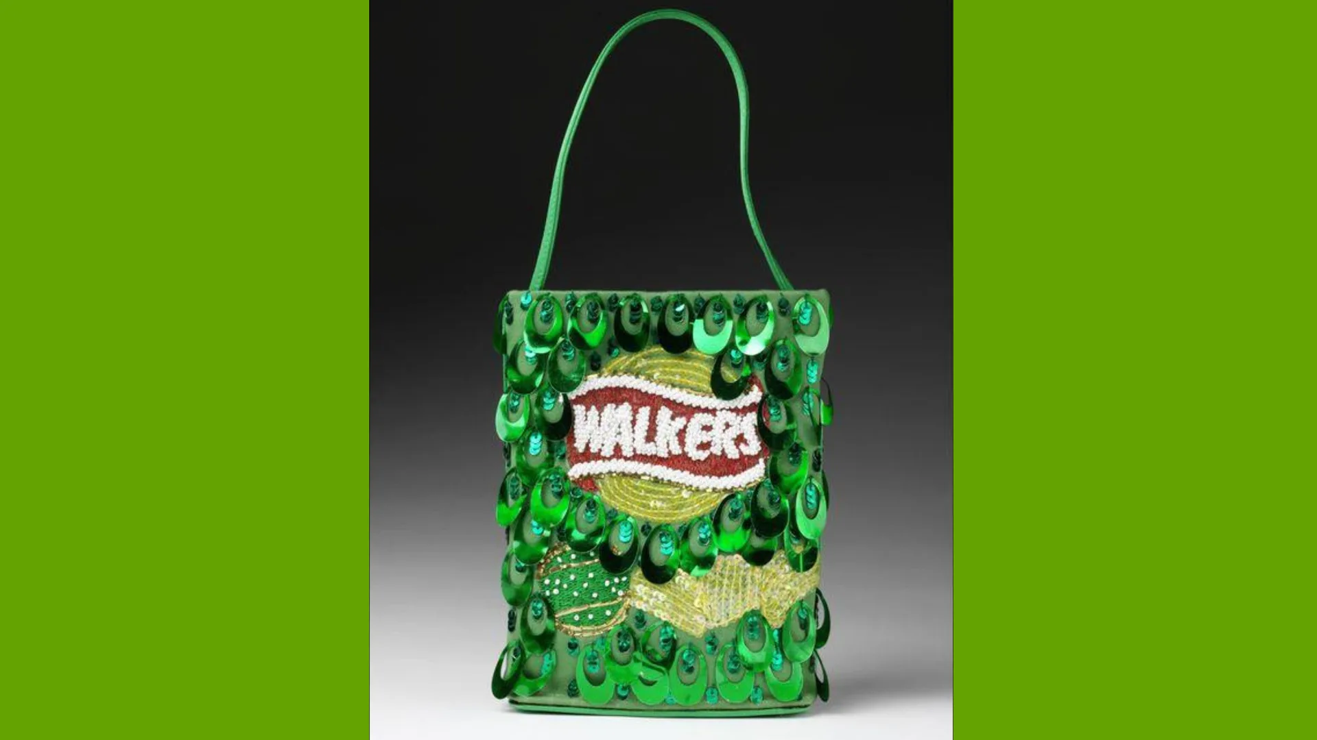 A photo of a V&A collection - a handbag made from green sequins and beads in the design of a Walkers crisp bag with a green chain