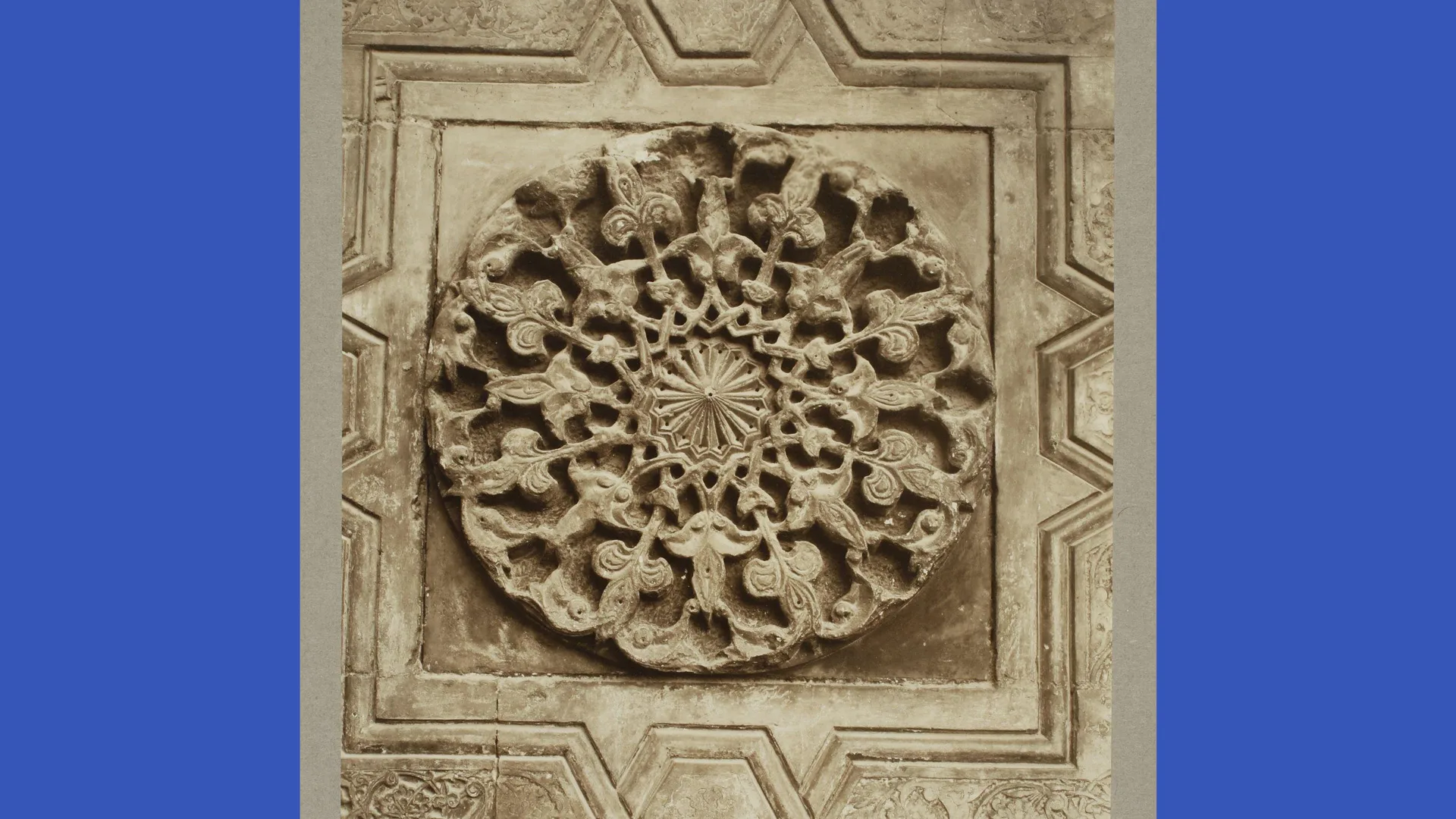 A photograph of an ornate stone structure panel that would have been on a doorway in India with blue borders