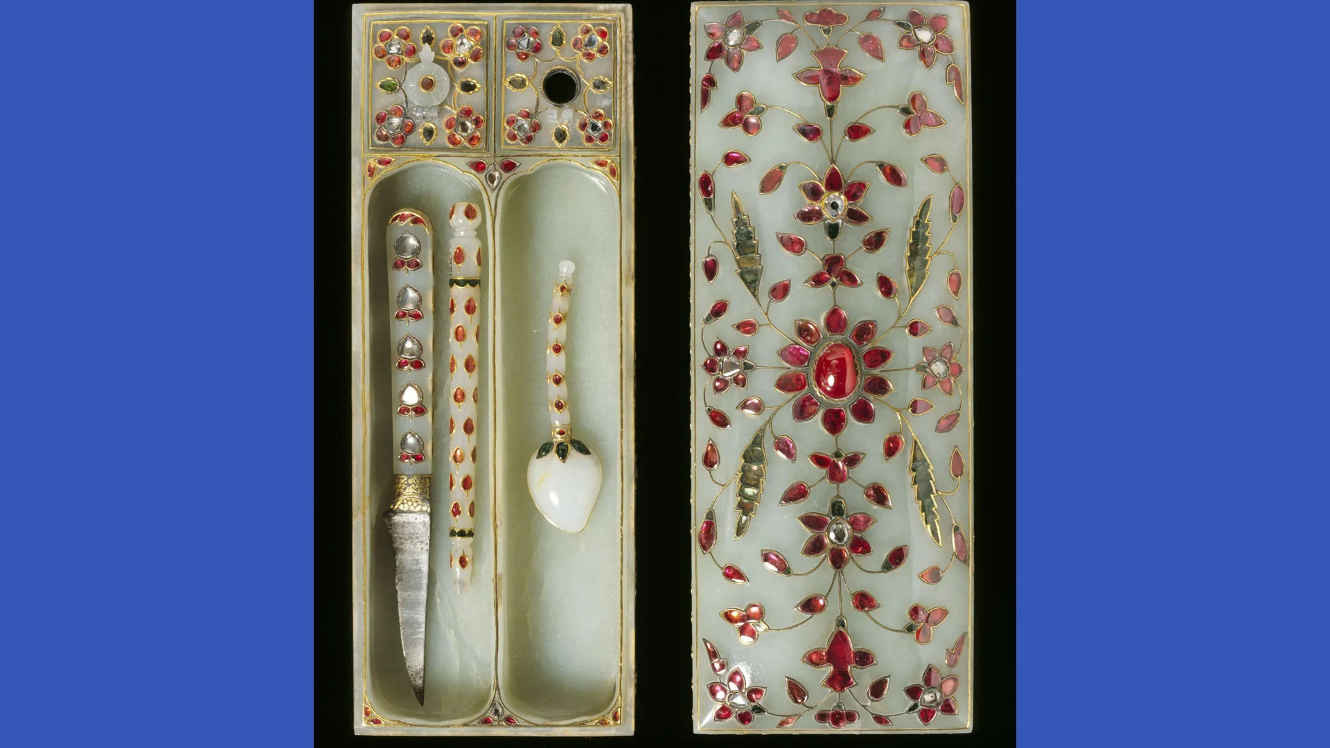 A photograph of a 17th century pen box in a light green and utensils with red glass floral decorations surrounded by blue borders