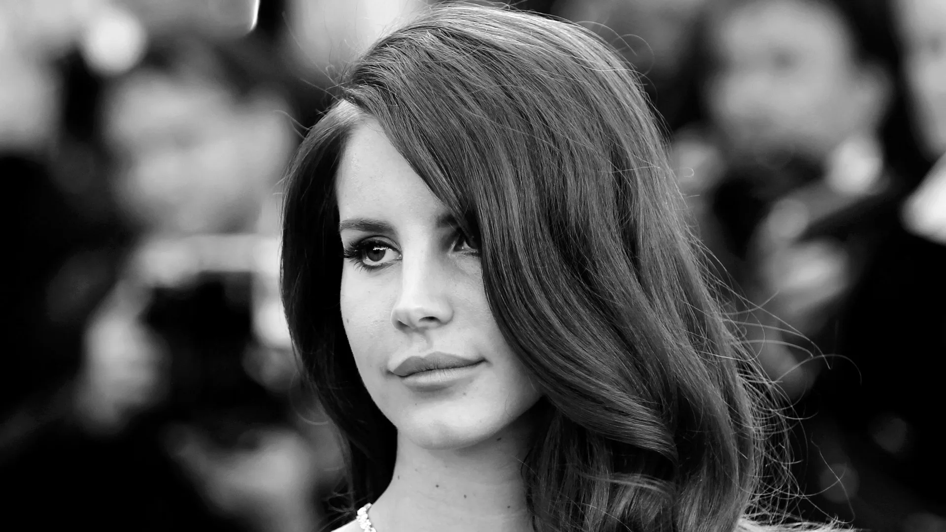 A black and white photograph of the singer Lana Del Ray looking off to the side with her hair swept over one half of her face