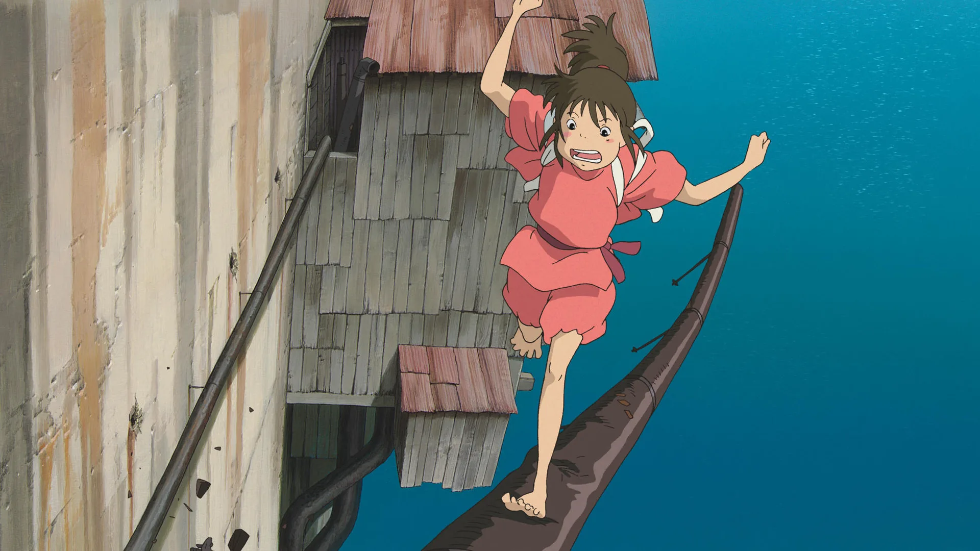 A still from the film Spirited Away showing Chihiro walking on a tight rope over the sea with a scared expression on her face