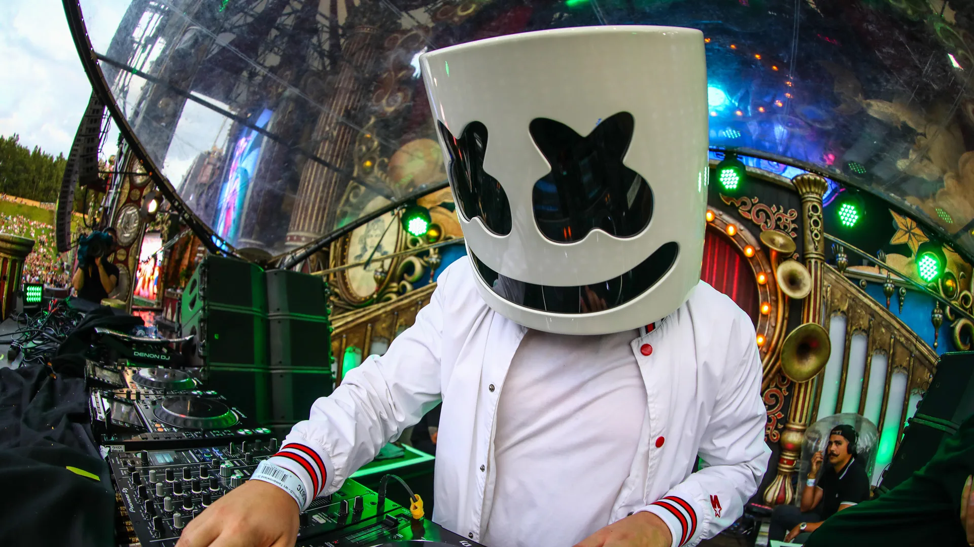 A photograph of the DJ Marshmello performing on decks in his famous white tin can head with black crossed out eyes and smile